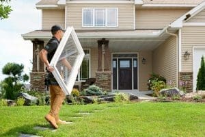 RBA of Greater Wisconsin installer carrying Fibrex replacement window into two-story home.
